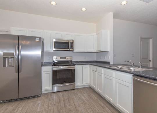 A kitchen with a stainless steel refrigerator, microwave, oven, and sink.