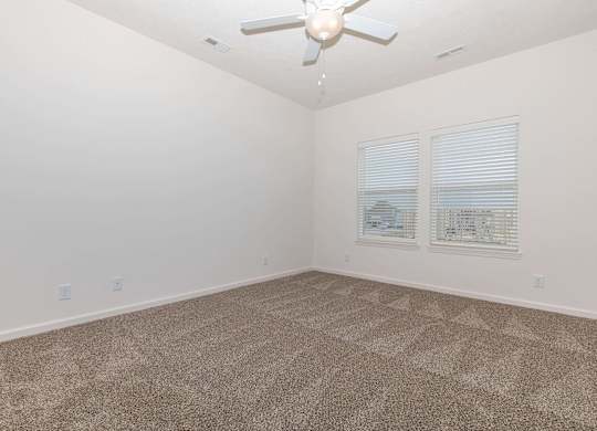 A room with a ceiling fan and carpeted floor.