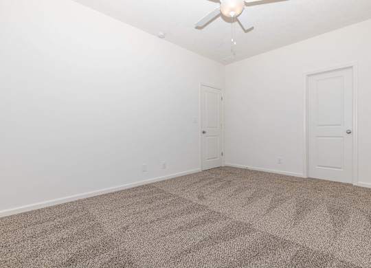 A room with a ceiling fan and carpeted floor.