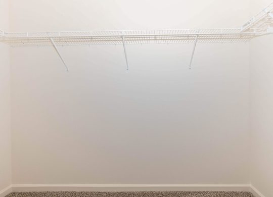 Empty white room with a shelf on the wall.