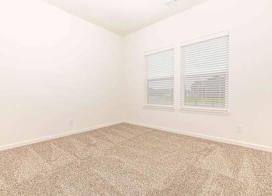 A room with carpeted floor and two windows.