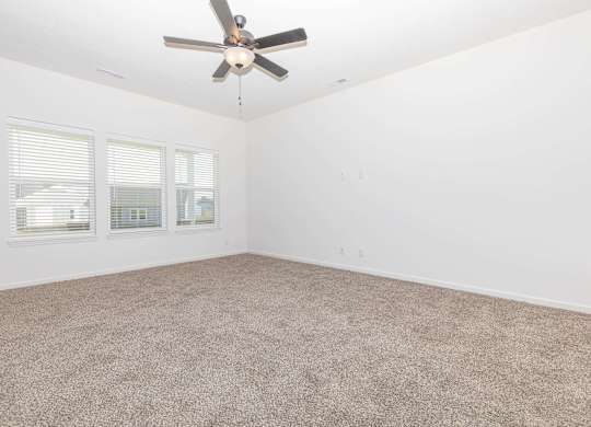 A room with a ceiling fan and carpeted floor.