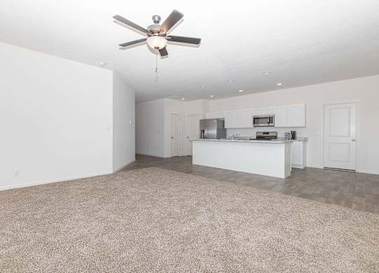 A room with a ceiling fan and a kitchenette.