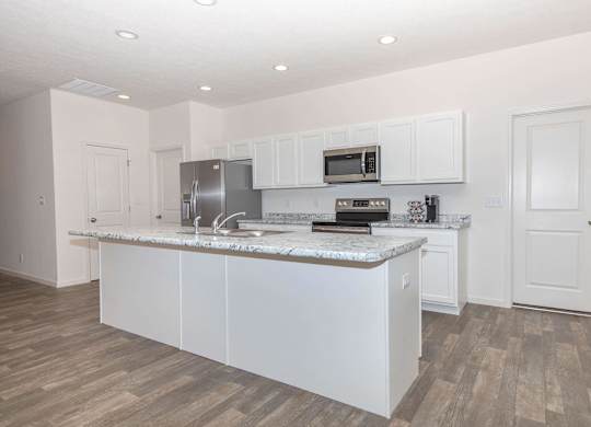 A kitchen with white cabinets and a marble countertop.