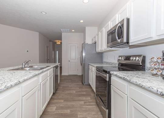 A kitchen with white cabinets and a marble countertop.