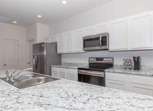 A kitchen with granite countertops and white cabinets.