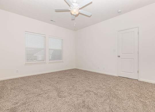 A room with a ceiling fan and carpeted floor.
