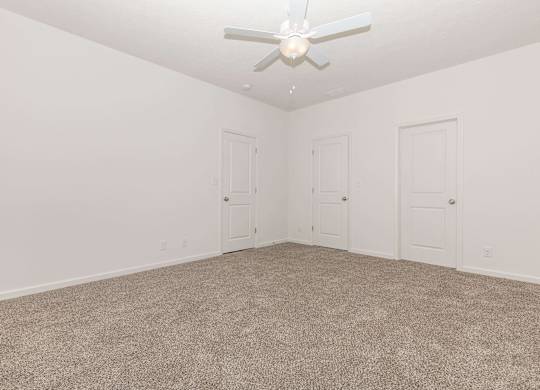 A room with a ceiling fan and carpeted floor.