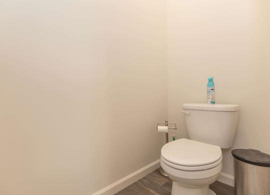 A white toilet with a roll of toilet paper on the wall.