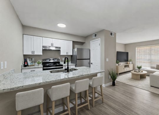 A modern kitchen with a marble countertop and bar stools.