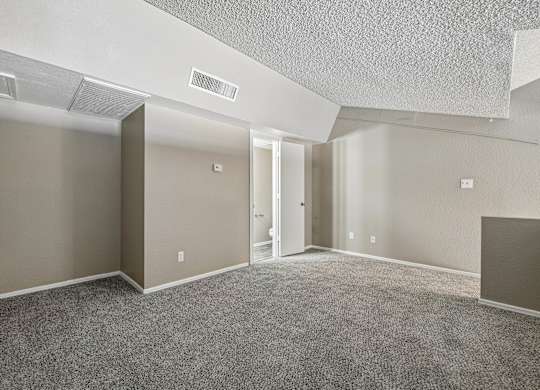 A spacious room with carpeted floor and a ceiling fan.