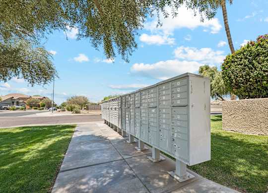 A long row of mailboxes are lined up on a sidewalk.