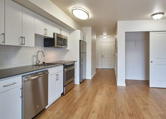 A kitchen with white cabinets and a wooden floor.