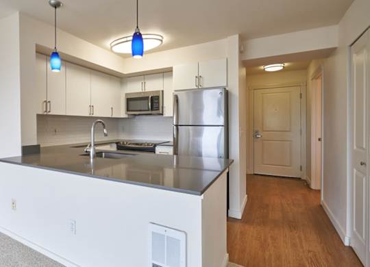 A kitchen with a stainless steel refrigerator and a microwave above the stove.