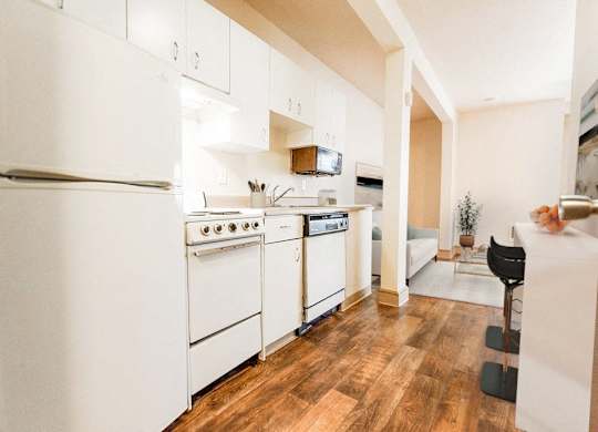 a kitchen with white appliances and a wood floor at Zindorf, Seattle, WA