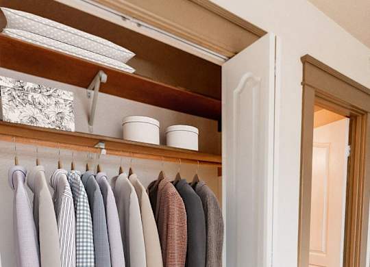 a closet with clothes hanging on a rack and a door to the bathroom at Zindorf, Seattle, Washington