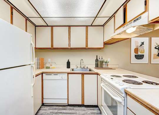 A kitchen with white appliances and wooden cabinets. at Autumn Village, Washington, 98354