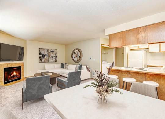 A living room with a fireplace and a dining table. at Autumn Village, Washington