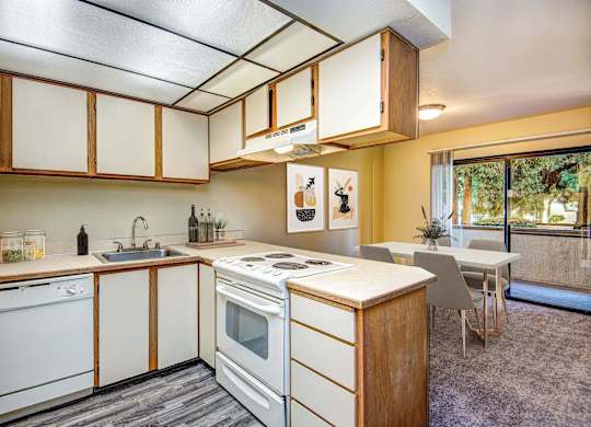 A kitchen with white appliances and wooden cabinets. at Autumn Village, Milton, WA, 98354