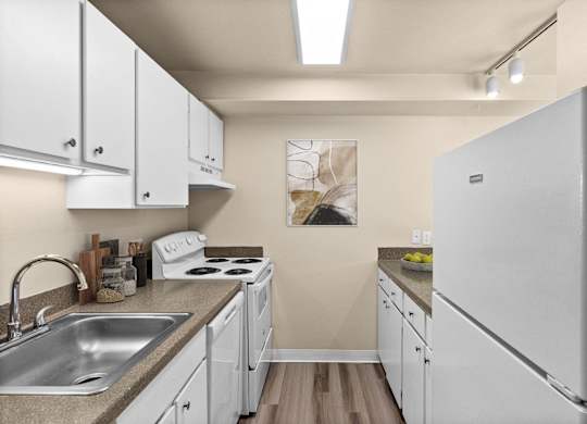A kitchen with white cabinets and a white fridge.
