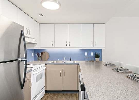 A kitchen with white cabinets and a blue backsplash.