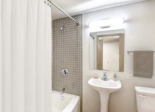 A white bathroom with a shower curtain and a white sink.