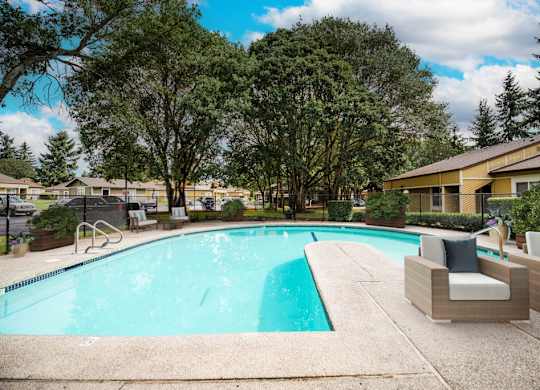 A swimming pool surrounded by trees and chairs.