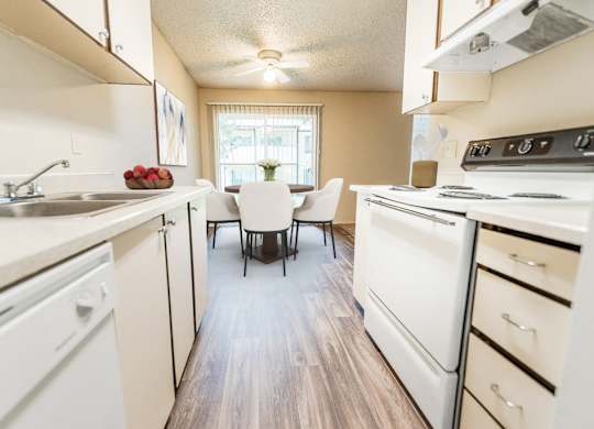 A kitchen with white appliances and a wooden floor.