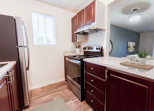A kitchen with a refrigerator, oven, and sink.