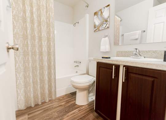 A white toilet sits in a bathroom with a white shower curtain.