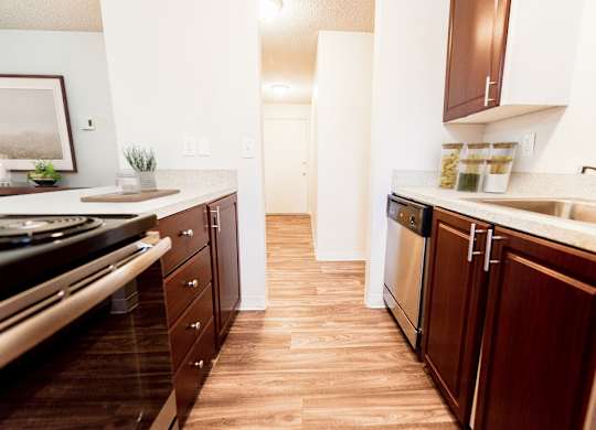 A kitchen with wooden floors and brown cabinets.