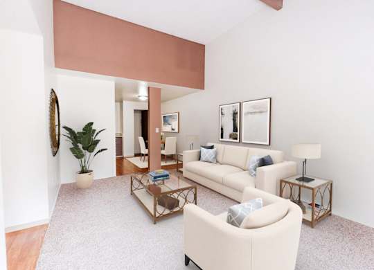 A living room with a beige couch, a coffee table, and a potted plant.