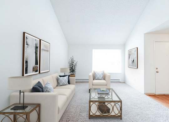 A living room with a white couch, a coffee table, and two framed pictures on the wall.