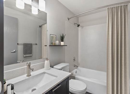 A modern bathroom with a white sink, toilet, and bathtub.