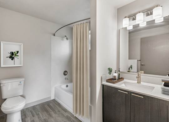 A white toilet sits next to a white bathtub in a bathroom.