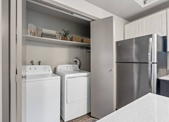 A modern kitchen with a refrigerator, washing machine, and dryer.