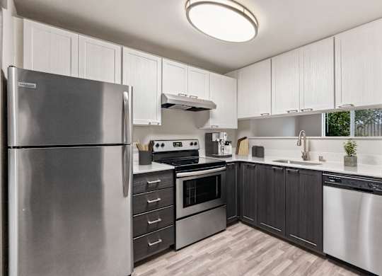 A modern kitchen with a stainless steel refrigerator and wooden flooring.