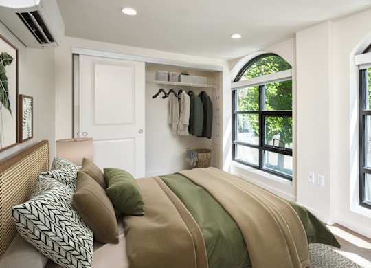 A bedroom with a large bed and a window overlooking a street.