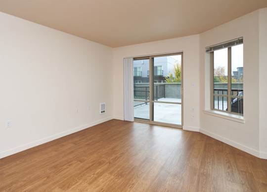 Empty room with wooden floors and sliding glass doors.