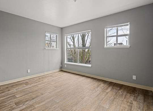 A room with wooden floors and two windows.