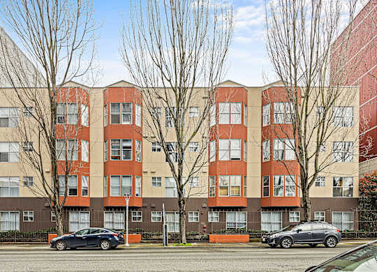 A black car is parked in front of a red building.