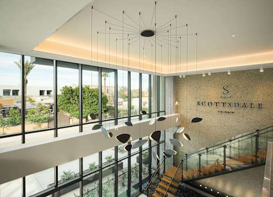 A modern interior of a building with a glass staircase and a hanging light fixture.