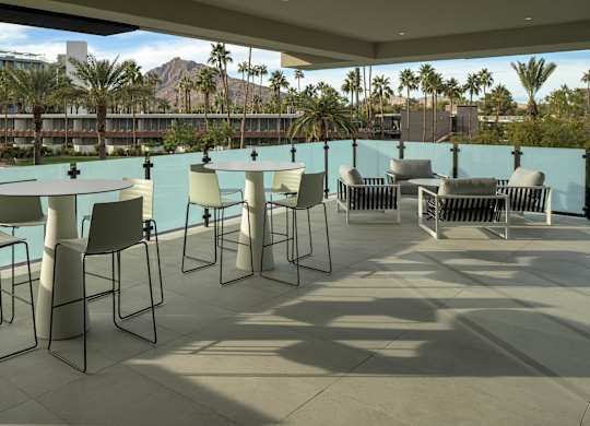 A patio with white chairs and a table with a blue wall.