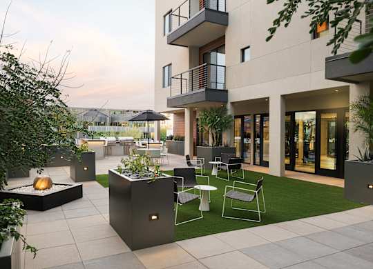 A modern patio with a fire pit and seating area.