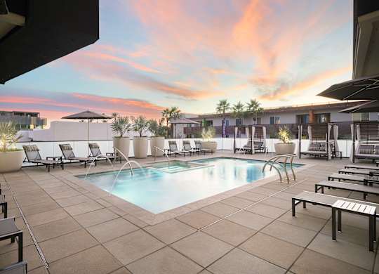 A pool surrounded by lounge chairs and umbrellas.