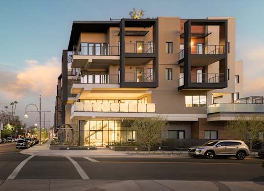 A modern apartment building with cars parked in front.