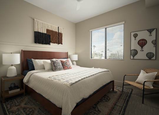 A bedroom with a bed, a chair, and a window.