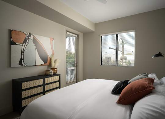 A bedroom with a large bed and a painting on the wall.