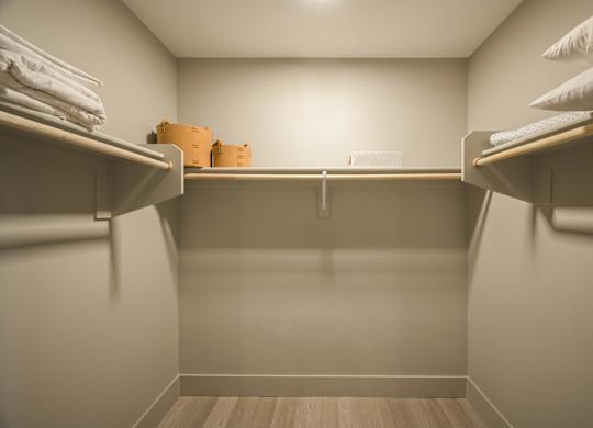 A small, empty closet with a wooden floor and white walls.