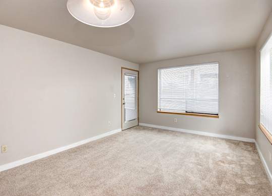 Seattle Apartments-  Living area with a large window and beige carpet
